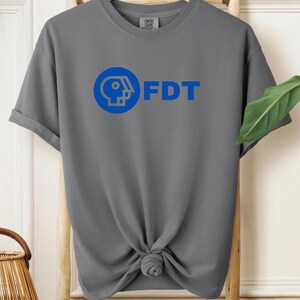May include: Gray t-shirt with a blue logo and the text "FDT" printed on the front.
