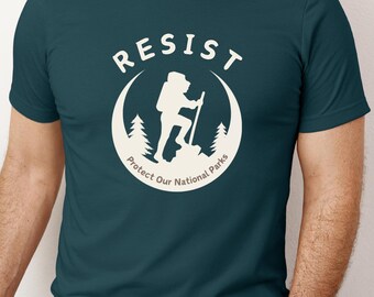 May include: A teal blue t-shirt with a white graphic of a hiker in a national park. The graphic says "Resist Protect Our National Parks".