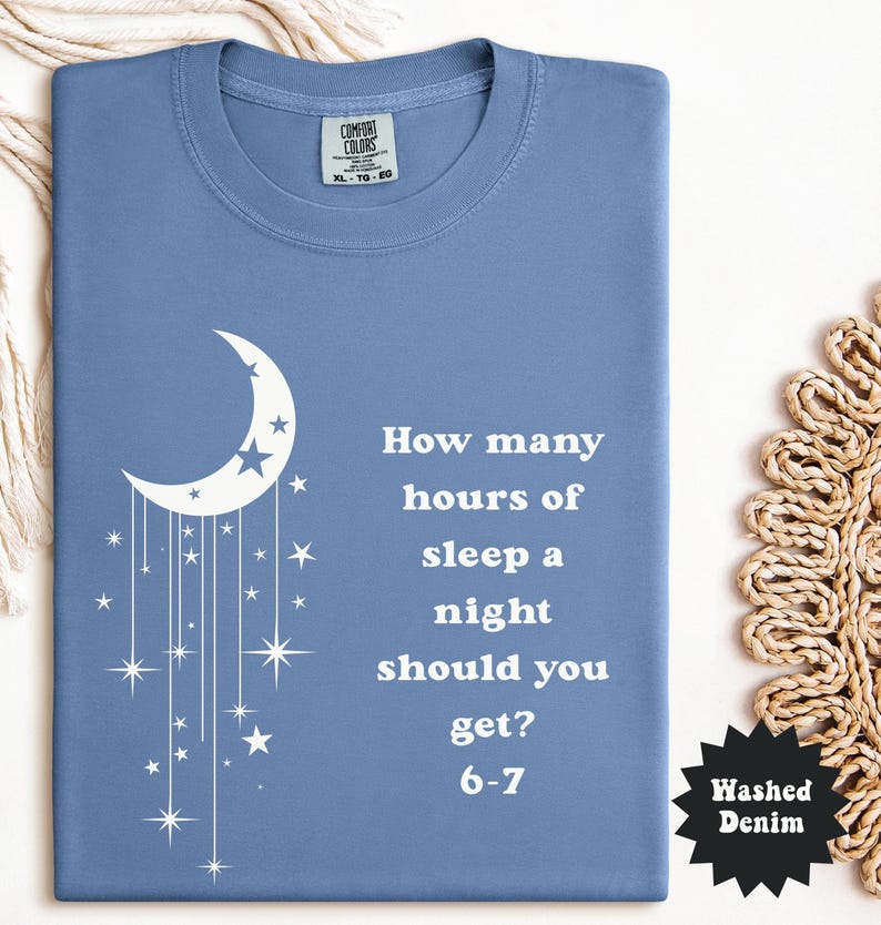 May include: A blue Comfort Colors t-shirt with a white crescent moon and stars design. The shirt features the text "How many hours of sleep a night should you get? 6-7". The shirt is size XL-TG-EG.
