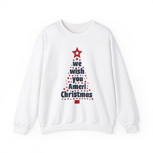 Puede incluir: Sudadera blanca de cuello redondo con un diseño de árbol de Navidad. El árbol está compuesto por estrellas rojas y azules, con las palabras "we wish you Ameri Christmas". Una estrella roja corona el árbol.