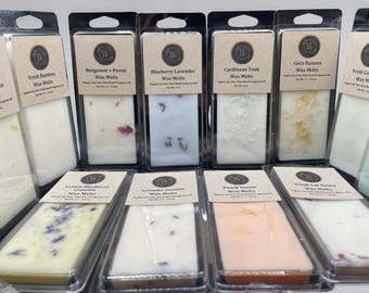 May include: A collection of rectangular wax melts in clear plastic packaging with tan labels. Each label displays a scent name, such as Lemon Verbena, Blueberry Lavender, or Peach Nectar, and states a net weight of 2 oz for the organic soy wax.
