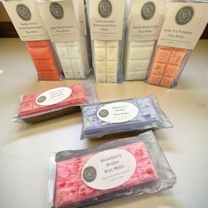 May include: A selection of scented wax melts in flavours such as Vanilla Sweet Potato Brown Sugar, Apple Buttercream, and Salted Caramel Butterscotch. Each wax melt is packaged in a clear plastic wrapper with a label. The melts are in shades of orange, white, and pink.