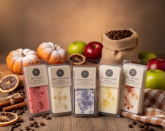 May include: Five rectangular plastic containers of wax melts, each with a label reading Apple Cinnamon, Sweet Vanilla Caramel, Blueberry Cheesecake, My Grandma's Kitchen, or Apple Cider Donut. The melts are pink, white, purple, yellow, and white.