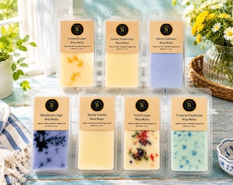 May include: Seven rectangular clear plastic clamshell containers of wax melts arranged in two rows. Each features a tan label with the SS logo, scent name, and Net Wt. 3.2 - 3.4 oz. Scents include Crème Brulee, Island Fresh Gain, Fabric Softener, Blackberry Sage, Honey Vanilla, Froot Loops, and Tropical Daydream.