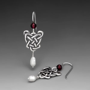 May include: Silver Celtic knot earrings with a red bead and a white pearl drop.