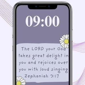 May include: A smartphone screen displays the time 09:00 in white text. The screen has a purple background with a quote from Zephaniah 3:17 and two daisy illustrations.