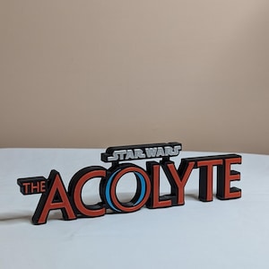 May include: A black and red logo for the Star Wars series "The Acolyte". The logo features a stylised circle with a blue and white ring.