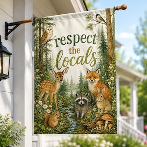 May include: A rectangular garden flag hanging from a black metal bracket, featuring a forest scene with a deer, fox, raccoon, rabbit, squirrel, owl, and bird. The text "respect the locals" is printed in green script and block lettering.