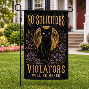 May include: A black garden flag featuring a central illustration of a black cat with yellow eyes sitting in front of a large gold moon. Purple flowers surround the cat. The text reads NO SOLICITORS at the top and VIOLATORS WILL BE HEXED at the bottom.
