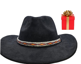 May include: A black cowboy hat with a decorative band featuring red, orange, and yellow geometric patterns. A small red gift box with a gold bow is next to the hat. The hat has a wide brim and a rounded crown.