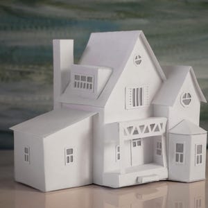 May include: A detailed, all-white miniature house model. The model features multiple levels, a chimney, dormer windows, and a small porch with decorative supports. The house has a classic architectural design, with a focus on symmetry and clean lines.