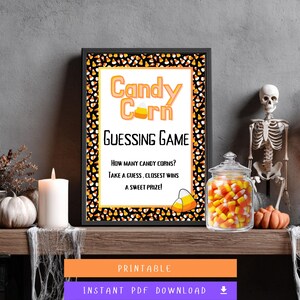 Peut inclure: Une affiche encadrée sur le thème d'Halloween avec le texte "Candy Corn Guessing Game". L'affiche est bordée de bonbons au maïs. Un bocal en verre rempli de bonbons au maïs, un squelette et une citrouille sont également visibles.