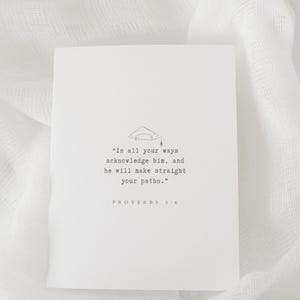 May include: A white card with a black and white illustration of a graduation cap. The text on the card reads "In all your ways acknowledge him, and he will make straight your paths." Proverbs 3:6