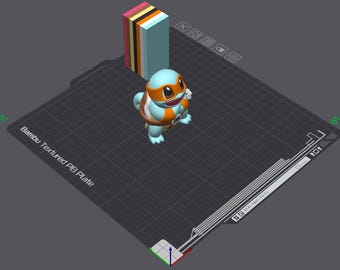 May include: A 3D-printed figurine of a cartoon turtle character, featuring blue, orange, and white colors. The turtle is standing on a textured black surface, with a stack of colorful rectangular blocks in the background.
