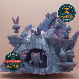 May include: A 3D-printed model of a fantasy cave scene with several cartoon creatures. The model is primarily blue and features crystal formations, rock formations, and the text "SLA TESTED" and "HueTR3D APPROVED".