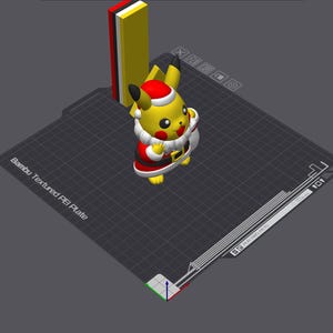 Może przedstawiać: Wydrukowana w 3D figurka Pikachu przebrana za Świętego Mikołaja, w czerwono-białym stroju i czapce, z białą torbą. Figurka jest żółta z czarnymi końcówkami uszu i czerwonymi policzkami. Żółty, czerwony i biały prostokątny obiekt znajduje się za figurką.