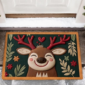 May include: A rectangular doormat featuring a smiling reindeer design. The mat has a dark green background with a brown reindeer face, red antlers, and floral accents. The border is a light brown color.