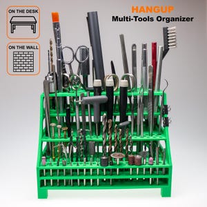 Puede incluir: Un organizador verde multiherramientas lleno de varias herramientas, incluyendo brocas, cepillos y tijeras. El organizador tiene múltiples ranuras y agujeros para sujetar las herramientas. El texto "HANGUP Multi-Tools Organizer" es visible.