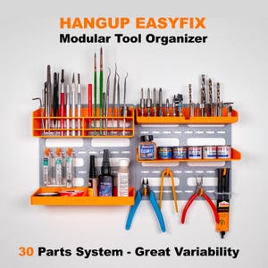 Puede incluir: Un organizador de herramientas de pared con 30 piezas, que presenta un tablero de clavijas gris con estantes y compartimentos naranjas. El organizador está lleno de varias herramientas, incluyendo destornilladores, alicates, botellas de pintura y otras herramientas pequeñas. El texto "HANGUP EASYFIX Modular Tool Organizer" está en la parte superior de la imagen, y el texto "30 Parts System - Great Variability" está en la parte inferior.