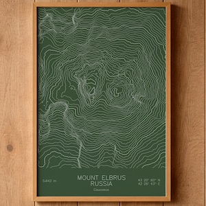 May include: A framed print featuring a topographic map of Mount Elbrus in Russia, with white contour lines on a dark green background. The text "Mount Elbrus Russia" is displayed, along with the mountain's elevation of 5,642 m.