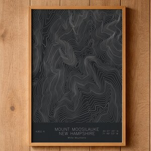 May include: A rectangular framed wall art print featuring a dark gray topographic map of Mount Moosilauke in New Hampshire. The print displays white contour lines and text at the bottom reading Mount Moosilauke, New Hampshire, 4,802 ft, White Mountains, 44 01' 25" N, 71 49' 53" W.