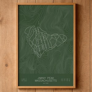 May include: A framed wall art print featuring a dark green topographic map of Jiminy Peak, Massachusetts. The design includes white contour lines, ski trail markings, and text stating Jiminy Peak, Massachusetts, est 1948, 2,380 ft, 45 trails.
