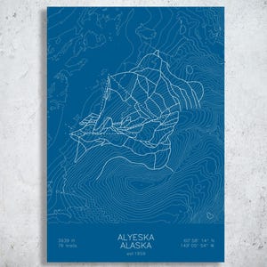 May include: A blue rectangular print featuring a white topographic map of Alyeska, Alaska. The design includes white contour lines, trail paths, and text reading Alyeska Alaska, est 1959, 3939 ft, 76 trails, and coordinates 60 58 14 N 149 05 54 W.