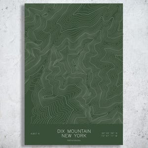 May include: A rectangular print featuring a dark green background with white topographic contour lines representing the terrain of Dix Mountain in New York. The text reads: DIX MOUNTAIN NEW YORK, 4,857 ft, 44 04 56 N, 73 47 11 W, Adirondacks.