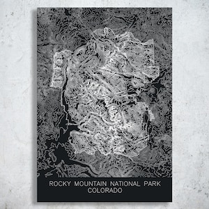 May include: A black and white topographic map print of Rocky Mountain National Park, Colorado. The map features detailed contour lines, creating a textured effect. The park's name and state are printed in white at the bottom.
