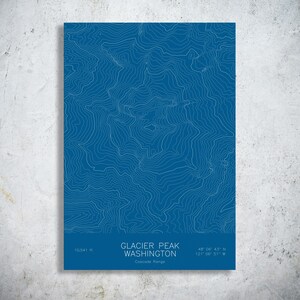 May include: A rectangular print featuring a blue background with white topographic contour lines of Glacier Peak, Washington. The text reads Glacier Peak Washington, Cascade Range, 10,541 ft, and the coordinates 48 degrees 06 minutes 43 seconds N, 121 degrees 06 minutes 51 seconds W.
