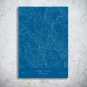 May include: A blue print of the Mont Blanc mountain range in France, featuring white contour lines. The print includes the mountain's elevation, coordinates, and the text "Mont Blanc France Alps."