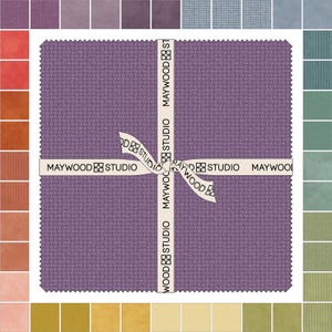 May include: A purple fabric square with a white ribbon tied around it. The ribbon has the text "Maywood Studio" printed on it.