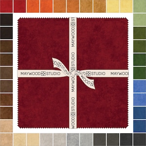 May include: A square of deep red fabric with a textured surface, crossed by a white ribbon printed with "MAYWOOD STUDIO." Surrounding the fabric are color swatches in shades of orange, brown, green, blue, and gray.
