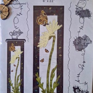 May include: A fabric panel with the text "Bloomin' Butterfly" and the dimensions 6" x 22". The design features a large flower with a butterfly and the words "Patch Abilities, Inc."