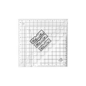 May include: A clear, square quilting ruler with grid lines and measurements in inches. Three black and white labels with the text "Bloc Loc" are placed on the ruler. The ruler is designed for precise fabric cutting and quilting.