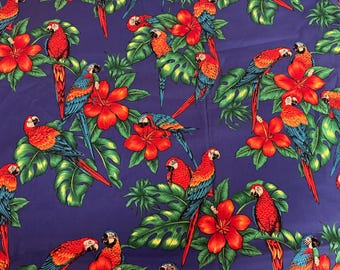 Puede incluir: Una tela estampada con un diseño repetido de loros coloridos, flores de hibisco rojas y hojas verdes grandes sobre un fondo azul oscuro. Los loros tienen plumas rojas, naranjas, azules y amarillas.
