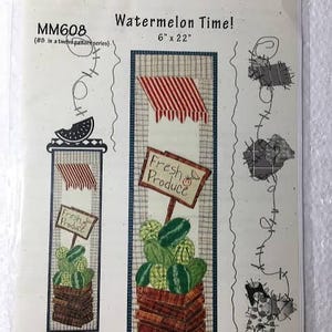 May include: A fabric panel titled "Watermelon Time!" featuring a design of watermelons in a wooden crate, with a sign that reads "Fresh Produce." The panel measures 6 inches by 22 inches.
