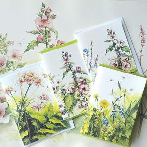 Könnte beinhalten: Vier florale Grußkarten mit Aquarellillustrationen von Wildblumen und Grün. Die Karten haben einen weißen Hintergrund mit grünen Rändern. Die Kunstwerke zeigen rosa, gelbe und blaue Blumen.