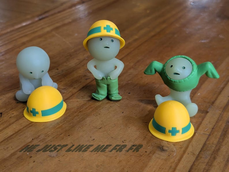 Puede incluir: Tres peque&ntilde;as figuras estilizadas. Una figura lleva un casco amarillo con una cruz verde y pantalones verdes. Otra figura lleva un traje verde. Una tercera figura est&aacute; arrodillada. El texto "ME JUST LIKE ME FR FR" est&aacute; en la parte inferior.