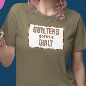 Op de afbeelding: Een groen T-shirt met een wit rechthoek met daarop de tekst "Quilters gonna quilt" in een bruin lettertype. De rechthoek is omgeven door een kleurrijk patchworkpatroon.