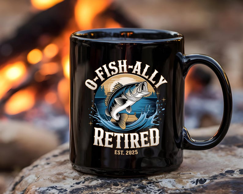Puede incluir: Taza de caf&eacute; negra con un gr&aacute;fico de un pez saltando fuera del agua. El texto en la taza dice "O-Fish-Ally Retired Est. 2025".