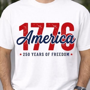 Pu&ograve; includere: T-shirt bianca con la scritta "1776 America" in rosso e blu, che celebra i 250 anni di libert&agrave;. Il design include stelle e un font invecchiato. Una maglietta classica per eventi patriottici.