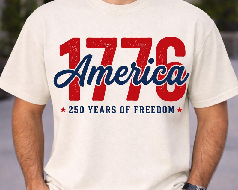 Pu&ograve; includere: T-shirt color crema con la scritta "1776 America" in rosso e blu. Sotto, "250 YEARS OF FREEDOM" con stelle rosse. La maglietta &egrave; in stile casual.