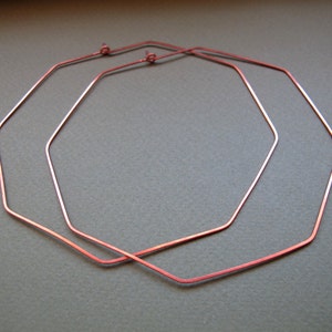 May include: A pair of octagonal hoop earrings made of copper wire. The earrings are simple and elegant, and they would be a great addition to any jewelry collection.