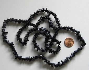 May include: A strand of dark blue gemstone chips, approximately the size of a US penny, strung on a clear thread.