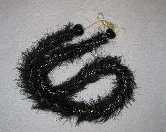 Black and light gold color crocheted eyelash lei, finished with black kukui nuts