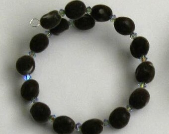 May include: A black seed bead bracelet with iridescent blue crystal accents. The bracelet is made of natural materials and has a simple, elegant design.