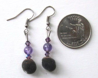 May include: A pair of earrings with purple beads and silver hooks. The earrings are hanging from a white surface. A US quarter is in the background for size reference.