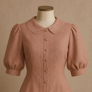 May include: A light brown dress with a white lace collar and a button-up front. The dress has short, puffed sleeves.