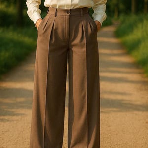 May include: Brown wide-leg trousers with pleats and a high waist. The trousers have a cuffed hem and are made of a smooth fabric.